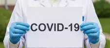 врач держит плакат с надписью COVID